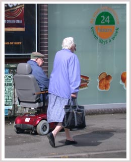 An image of a woman walking and a man in a mobility scooter